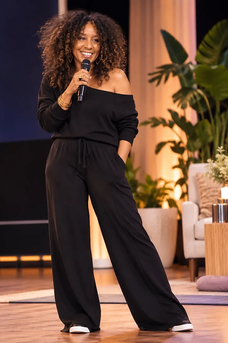 Nikki Thomas speaking into a microphone on a warmly lit stage